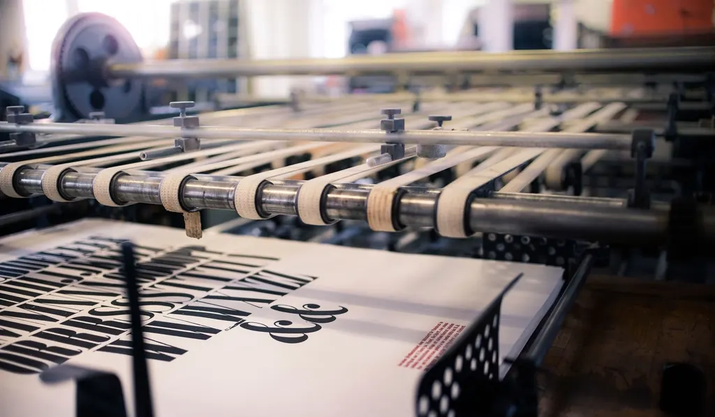 A press line running printed sheet stock through inked rollers.